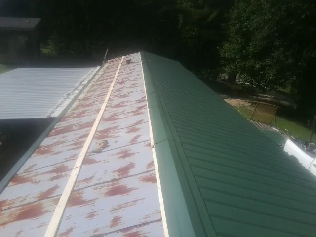 Old rusted panels beside newly installed green metal roofing — Wind Damage Roof Repair by Roofing Brothers in Crawfordsville