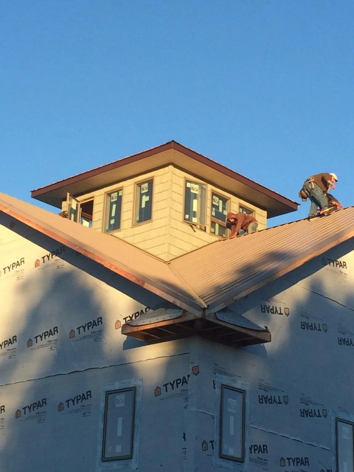 Roofers working around a rooftop cupola on a new metal roof at sunset — Roof Waterproofing in Crawfordsville by Roofing Brothers